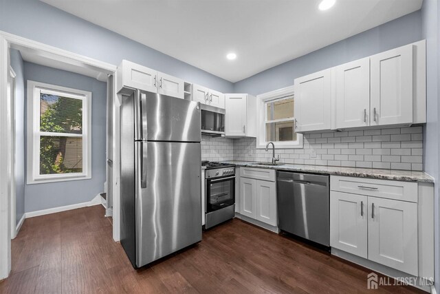 41 Guilden St, New Brunswick, NJ 08901 - kitchen featuring appliances with stainless steel finishes, light stone countertops, white cabinets, tasteful backsplash, and dark wood-style floors