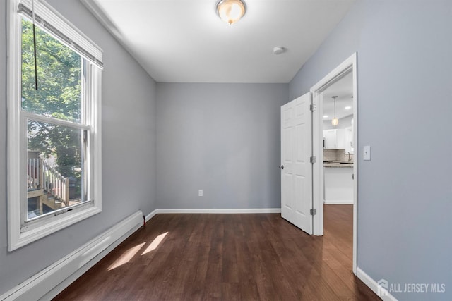 41 Guilden St, New Brunswick, NJ 08901 - unfurnished room featuring a baseboard heating unit, dark wood finished floors, and a smoke detector