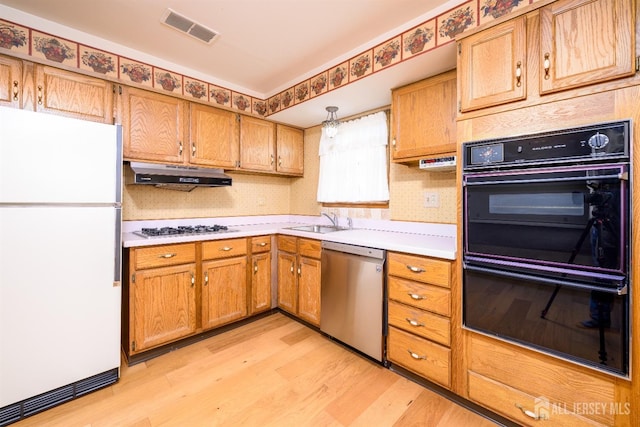 kitchen featuring visible vents, dobule oven black, under cabinet range hood, freestanding refrigerator, and dishwasher