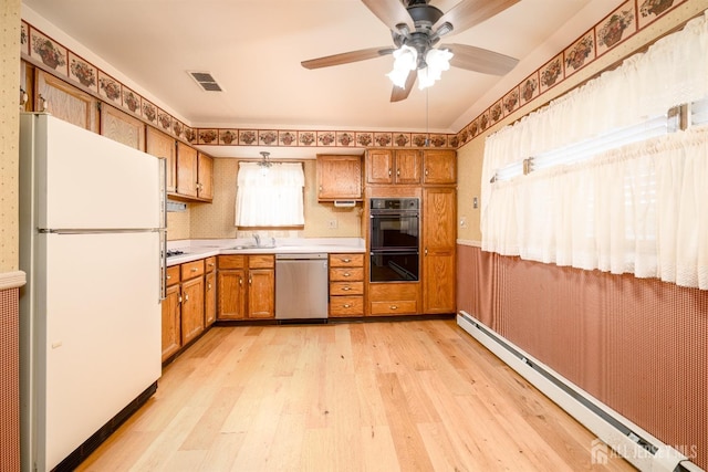 kitchen featuring brown cabinetry, visible vents, a baseboard radiator, freestanding refrigerator, and dishwasher