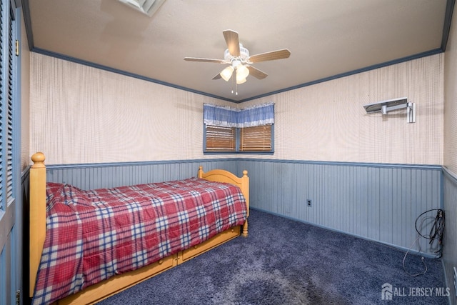 bedroom featuring crown molding, a wainscoted wall, carpet floors, and ceiling fan