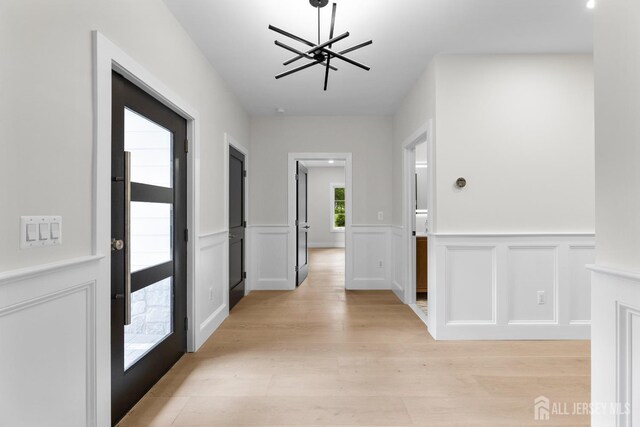 116 Hunt Dr, Princeton, NJ 08540 - foyer entrance with a chandelier, light wood-style flooring, a wainscoted wall, and a decorative wall