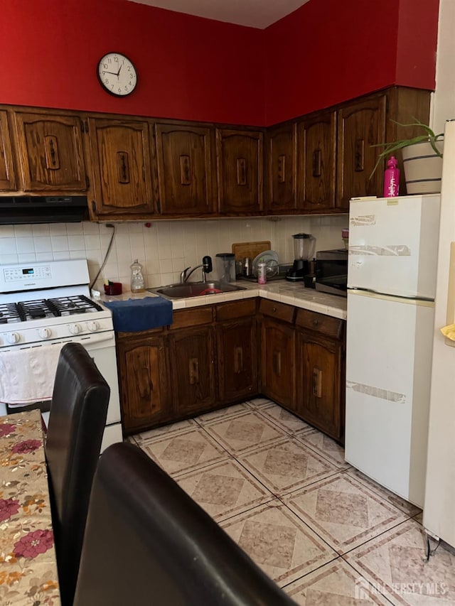 87-89 1st St, Perth Amboy, NJ 08861 - kitchen featuring tile counters, tasteful backsplash, white appliances, a sink, and ventilation hood