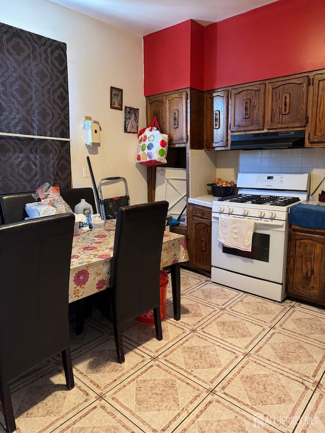 87-89 1st St, Perth Amboy, NJ 08861 - kitchen with under cabinet range hood, white gas stove, light countertops, and tasteful backsplash