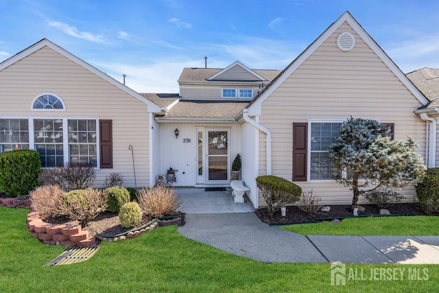 traditional home featuring a front yard and roof with shingles