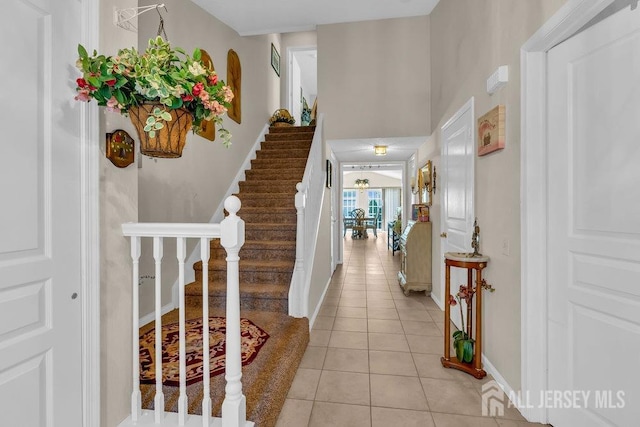 foyer entrance featuring stairs, light tile patterned floors, and baseboards