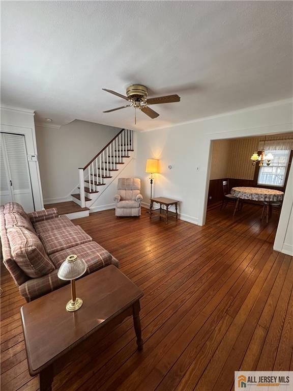 living room featuring ceiling fan with notable chandelier and dark hardwood / wood-style flooring