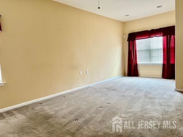 carpeted empty room featuring baseboards