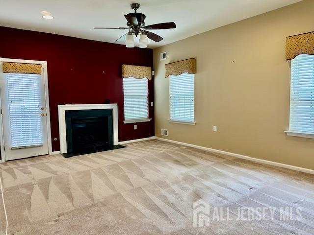 unfurnished living room with a ceiling fan, baseboards, and healthy amount of natural light