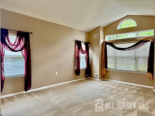 carpeted empty room with vaulted ceiling and baseboards