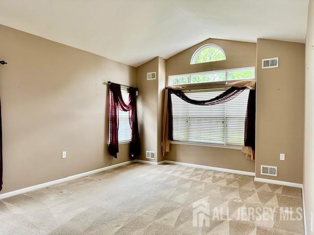 spare room with vaulted ceiling, carpet flooring, and baseboards