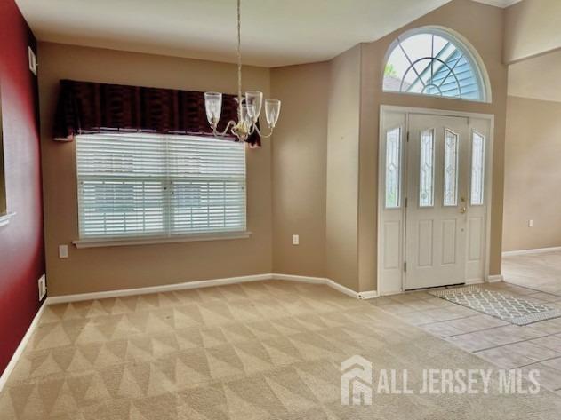 entrance foyer featuring a chandelier, plenty of natural light, baseboards, and light carpet