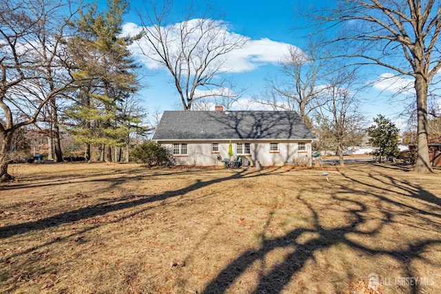 back of property with a chimney and a lawn