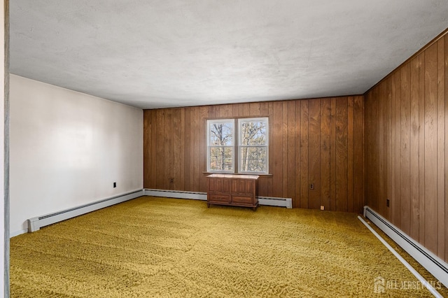 empty room featuring wood walls and baseboard heating