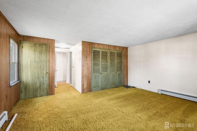 unfurnished bedroom with light carpet, wood walls, and baseboard heating