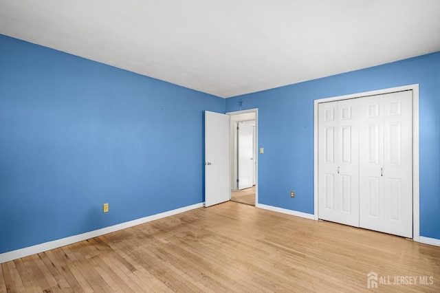 unfurnished bedroom with baseboards, a closet, and light wood-style floors