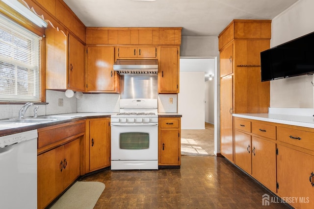 kitchen with white appliances, a sink, light countertops, brown cabinets, and wall chimney exhaust hood