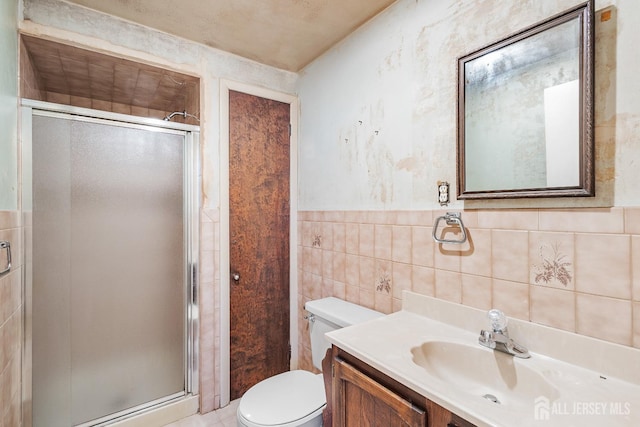 bathroom with toilet, a stall shower, vanity, and tile walls