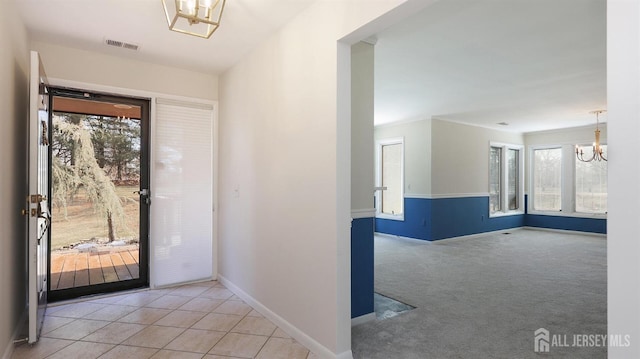 foyer entrance with a healthy amount of sunlight, light colored carpet, visible vents, and a notable chandelier