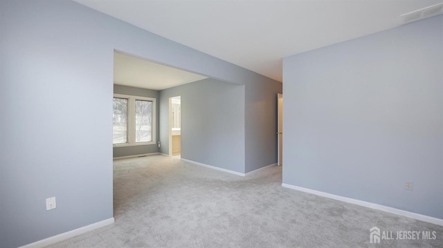 spare room featuring light carpet and baseboards