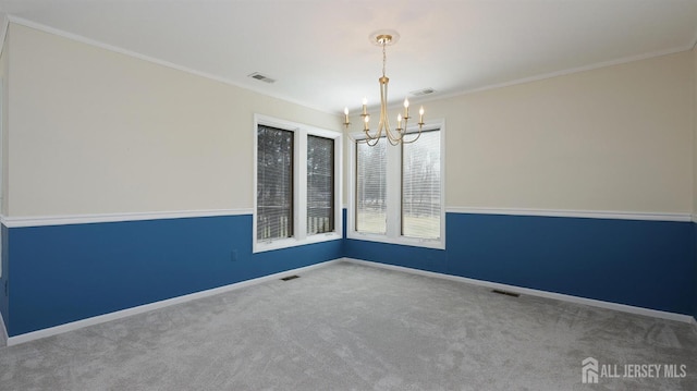 carpeted spare room with ornamental molding, visible vents, a notable chandelier, and baseboards