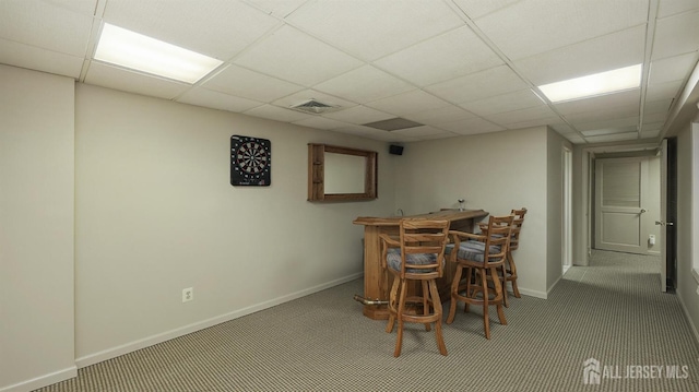 carpeted dining room with baseboards, visible vents, a drop ceiling, and a bar