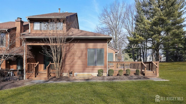 back of property featuring roof with shingles, a yard, and a deck