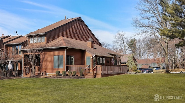 rear view of property with a shingled roof, a chimney, a deck, and a lawn