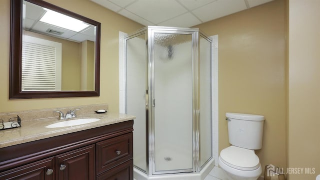 bathroom with visible vents, toilet, a shower stall, vanity, and a drop ceiling