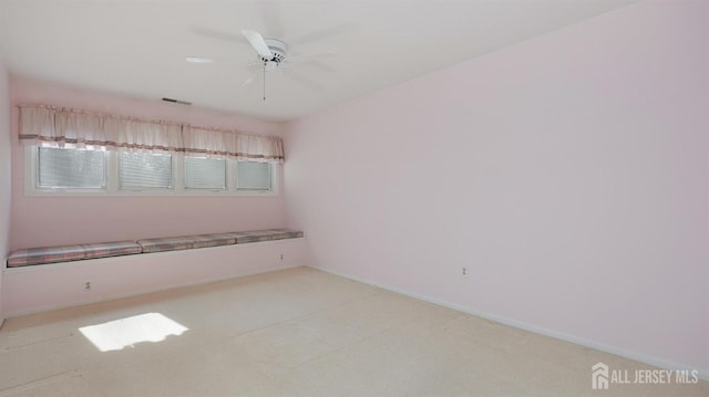 spare room featuring visible vents, a ceiling fan, and baseboards