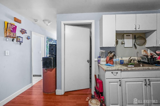 188 Seaman St, New Brunswick, NJ 08901 - kitchen with a sink, white cabinetry, wood finished floors, light countertops, and baseboards