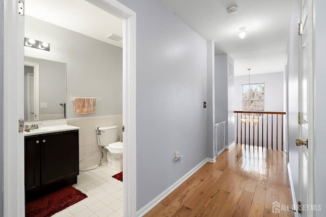 bathroom with hardwood / wood-style floors, vanity, tile walls, and toilet