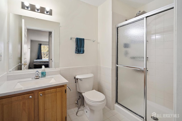 bathroom featuring toilet, a shower with shower door, tile patterned flooring, and tile walls