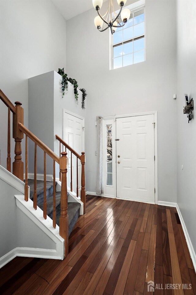 entrance foyer with a towering ceiling, an inviting chandelier, and dark hardwood / wood-style flooring