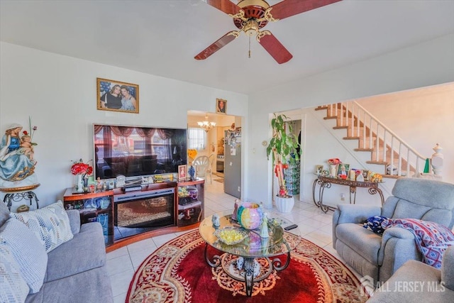 tiled living area with ceiling fan with notable chandelier and stairway