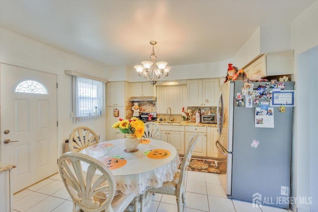 dining space with light tile patterned floors, a toaster, and a notable chandelier