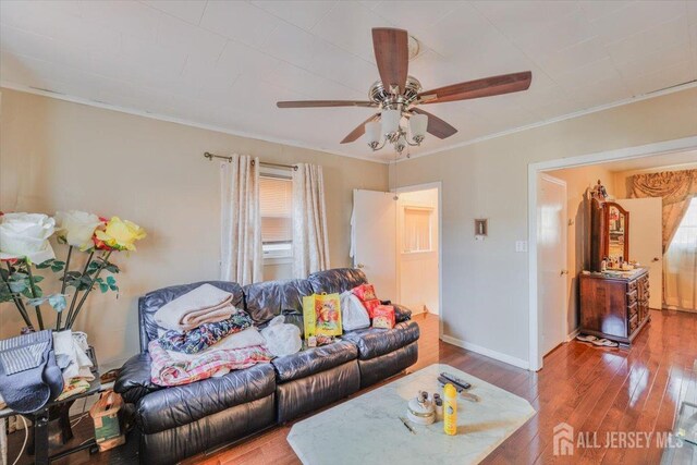 living room featuring baseboards, wood-type flooring, a wealth of natural light, and crown molding