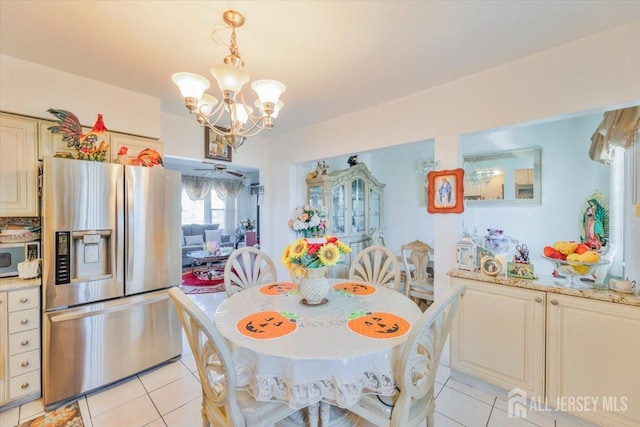 kitchen with light tile patterned floors, stainless steel fridge, pendant lighting, and a notable chandelier