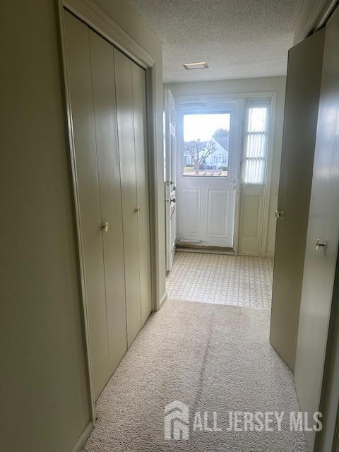 hallway featuring a textured ceiling and light carpet