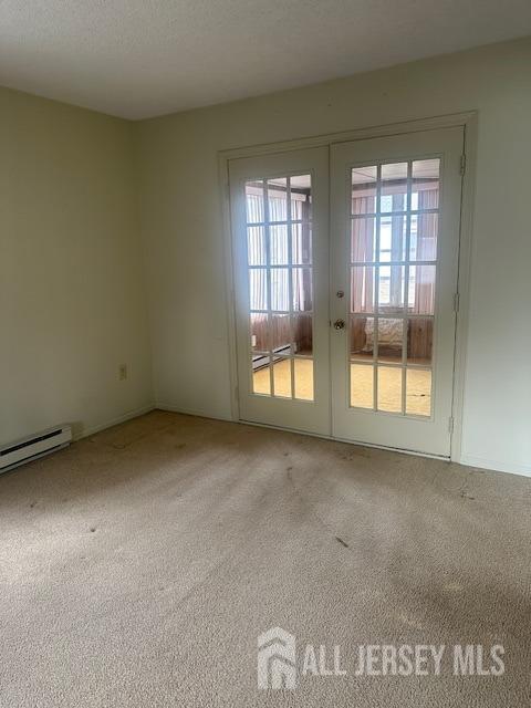 unfurnished room featuring baseboard heating, french doors, a textured ceiling, and carpet