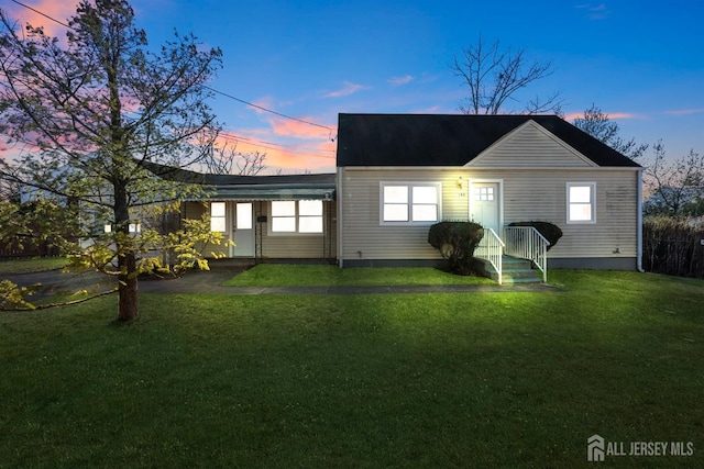 back of property at dusk featuring a yard