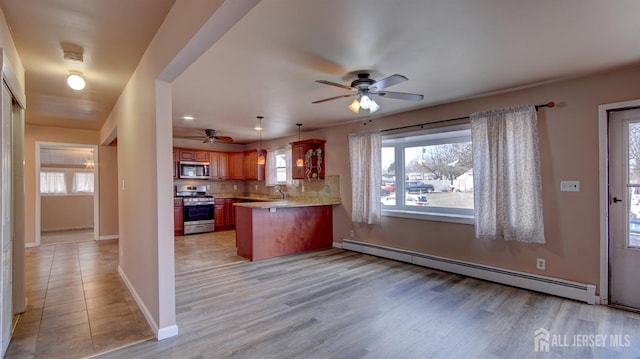 kitchen with baseboards, a peninsula, stainless steel appliances, light countertops, and a baseboard heating unit