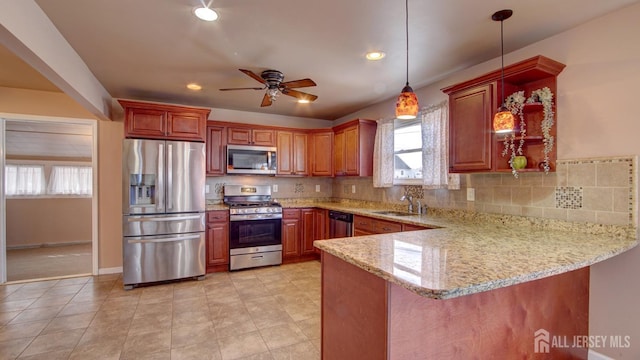 kitchen featuring light stone counters, stainless steel appliances, decorative backsplash, a sink, and a peninsula