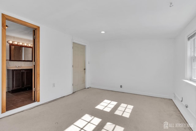 unfurnished bedroom with recessed lighting, ensuite bath, and a sink