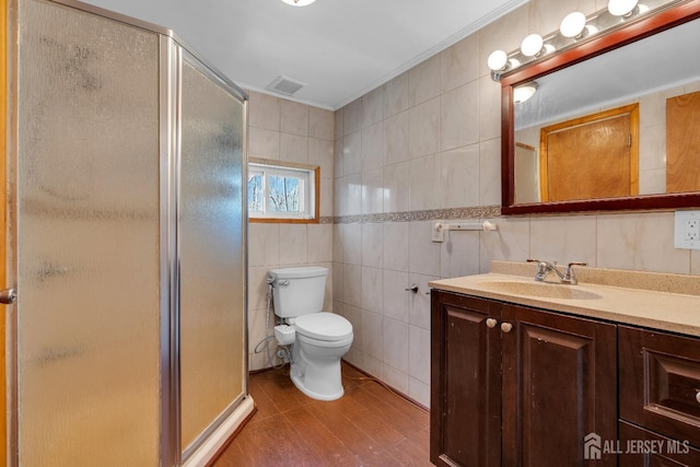 full bathroom with visible vents, a shower stall, vanity, and tile walls