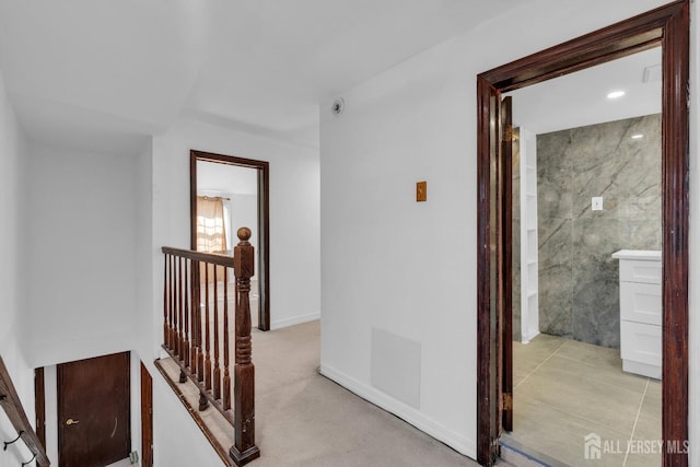 hall with an upstairs landing and light colored carpet