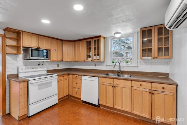 kitchen with backsplash, a wall mounted air conditioner, wood finished floors, white appliances, and a sink