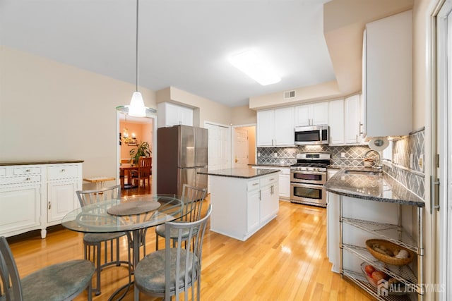 18 Stout Dr, Hillsborough, NJ 08844 - kitchen featuring appliances with stainless steel finishes, a kitchen island, backsplash, light wood-type flooring, and white cabinets