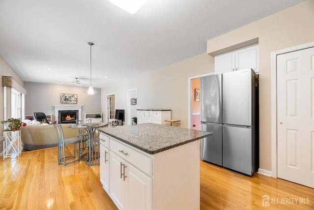 18 Stout Dr, Hillsborough, NJ 08844 - kitchen with freestanding refrigerator, light wood finished floors, a warm lit fireplace, a kitchen island, and white cabinets