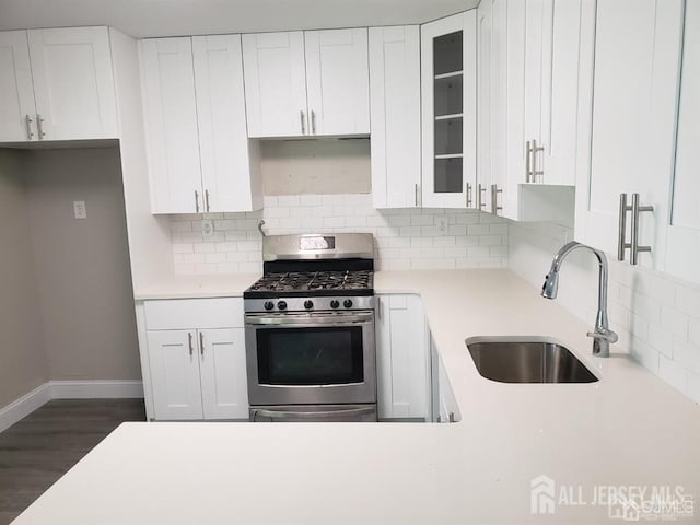 kitchen with gas range, white cabinetry, sink, and tasteful backsplash